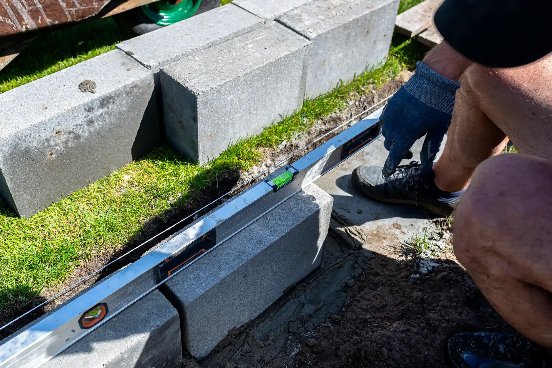 Arbejder med betonblokke til opbygning af en mur, med fokus på præcision og kvalitet.
